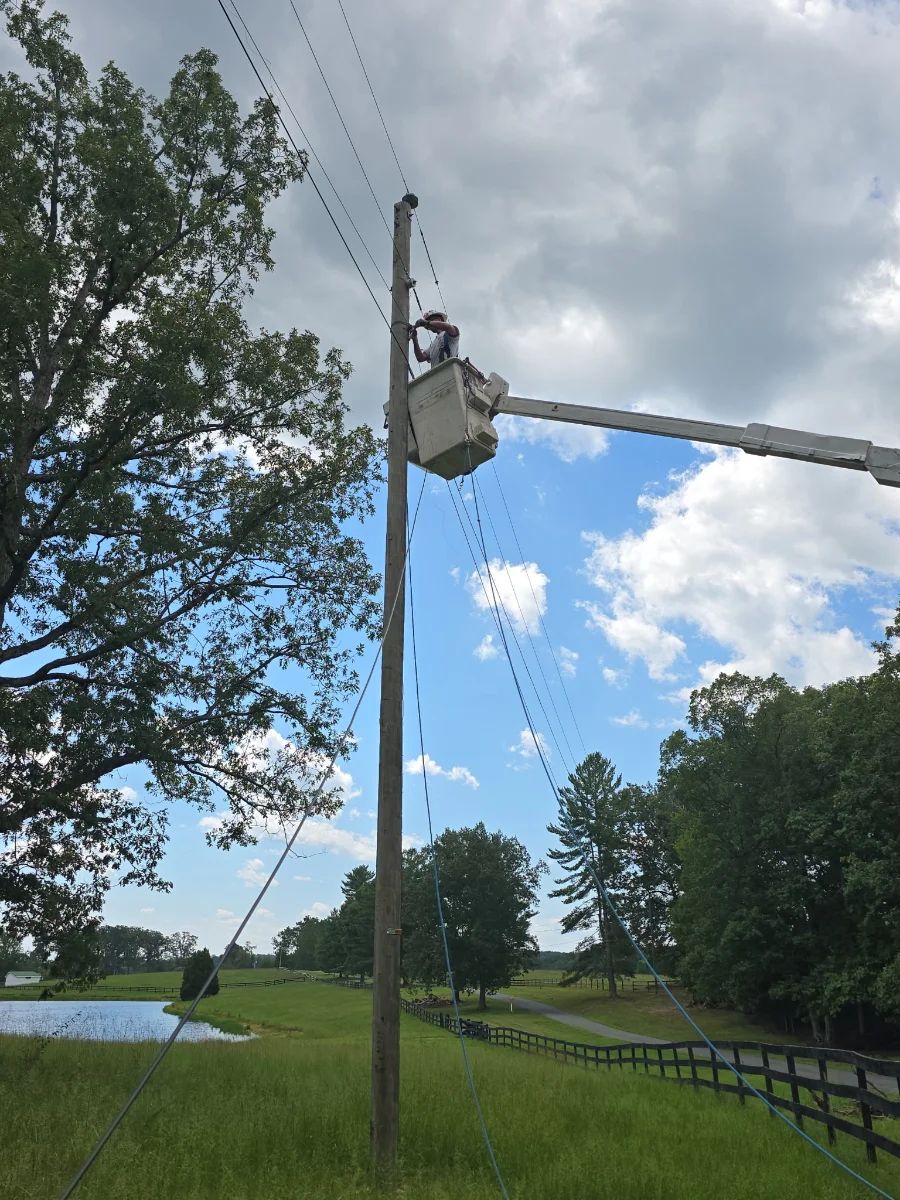 CMV lineman working from a bucket at the top of a pole line